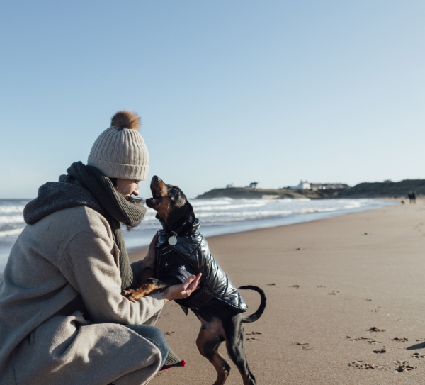 Young woman on a boach in Northumberland with her dog