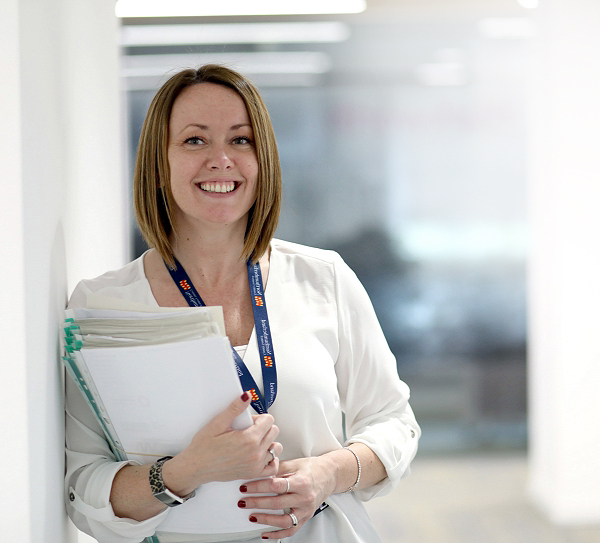 Woman in office smiling holding paperwork