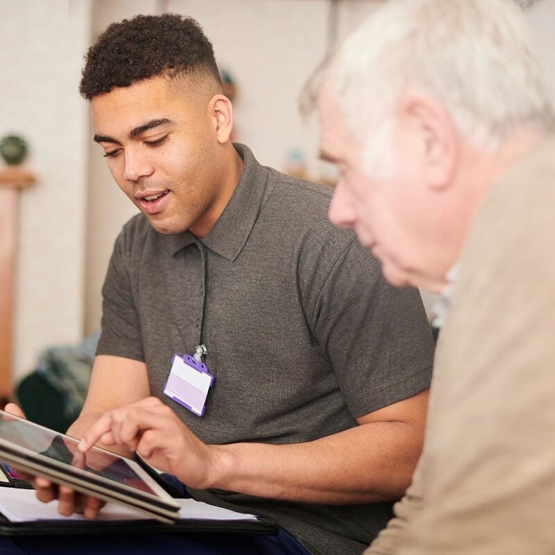 A male carer showing an older man information on an ipad