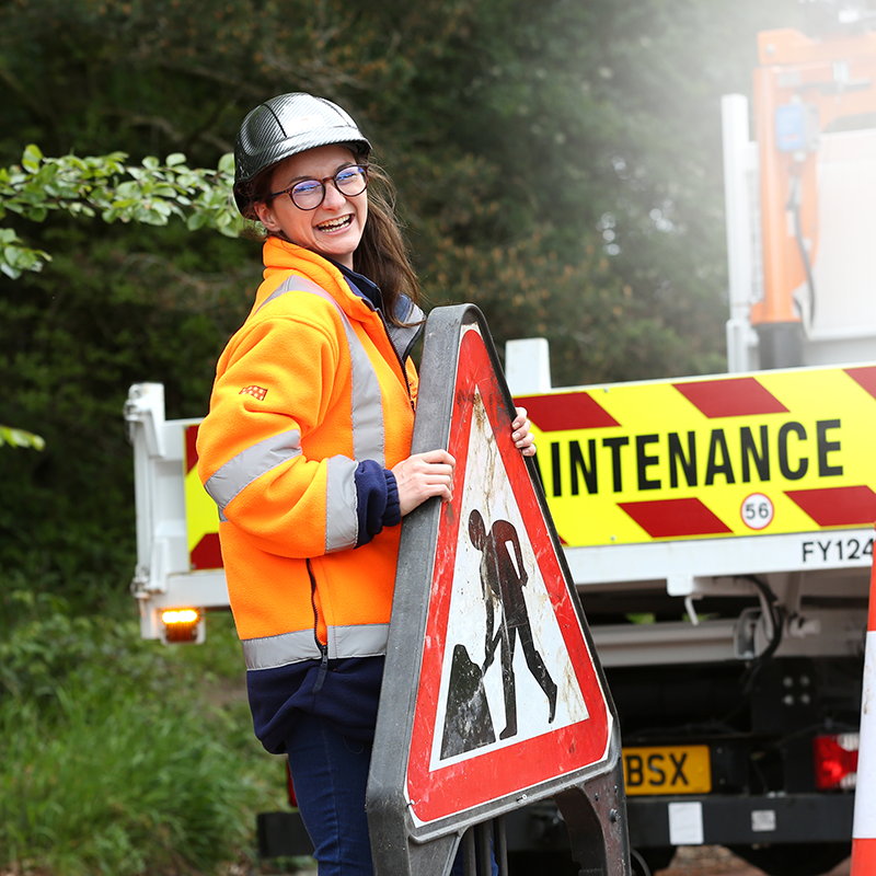 Young female worker putting up a road sign