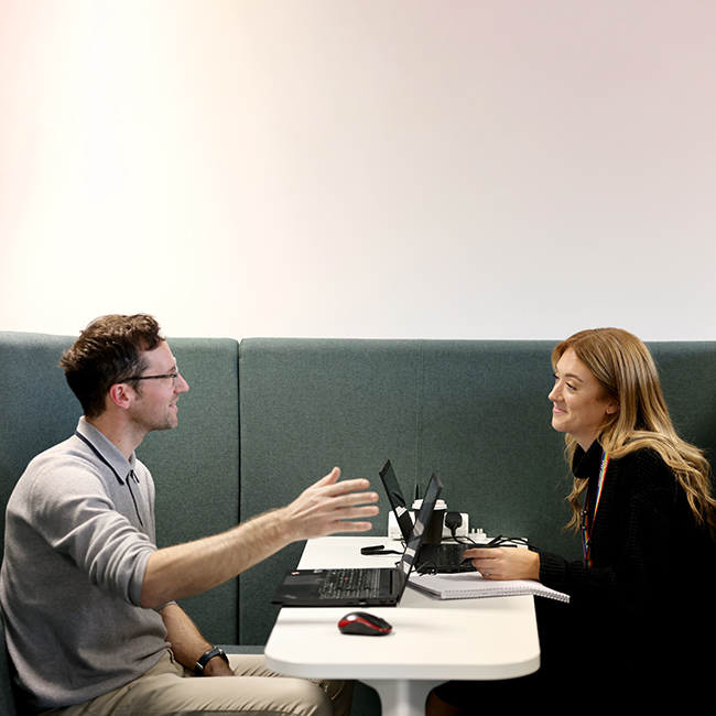 Man and woman sat in a booth having a meeting with a table between them