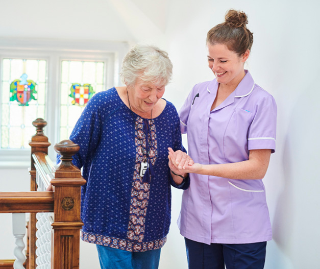 A carer helping an elderly lady up the stairs