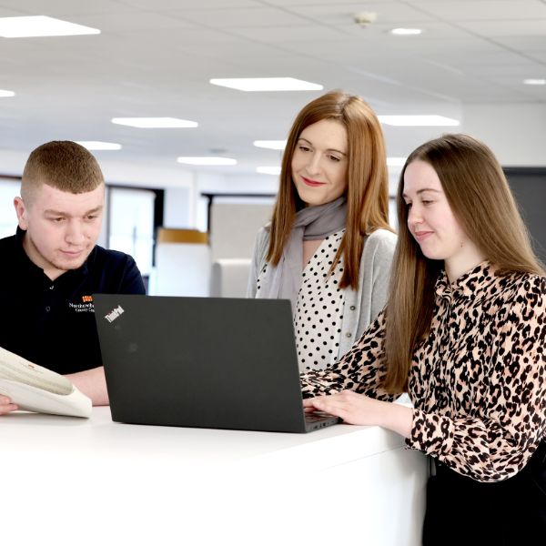 Man and two women looking at a laptop