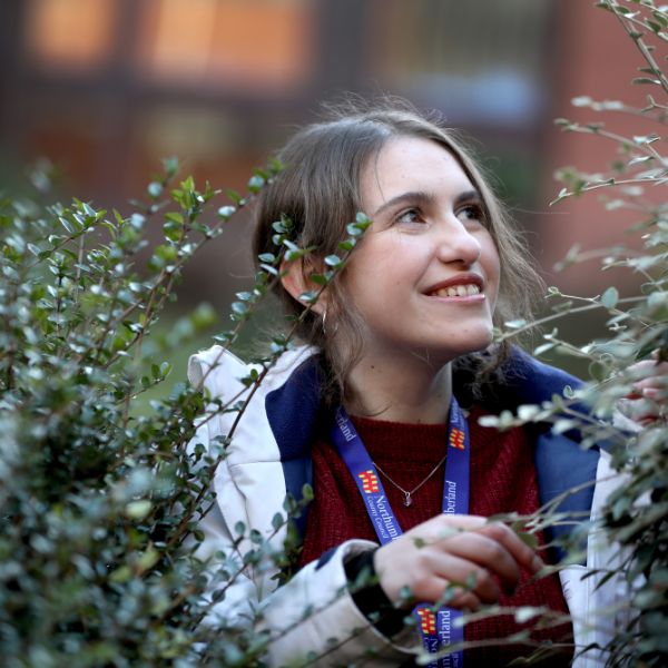 Female member of staff looking off to the right, inspecting a hedge